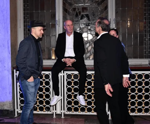 Three guests talking by a carved balustrade