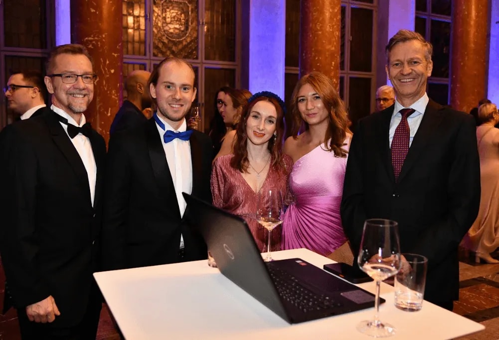 Partners and guests around a laptop demo at the Gala